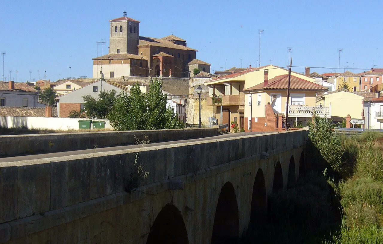Vista de un puente antiguo y una iglesia en Población de Campos.