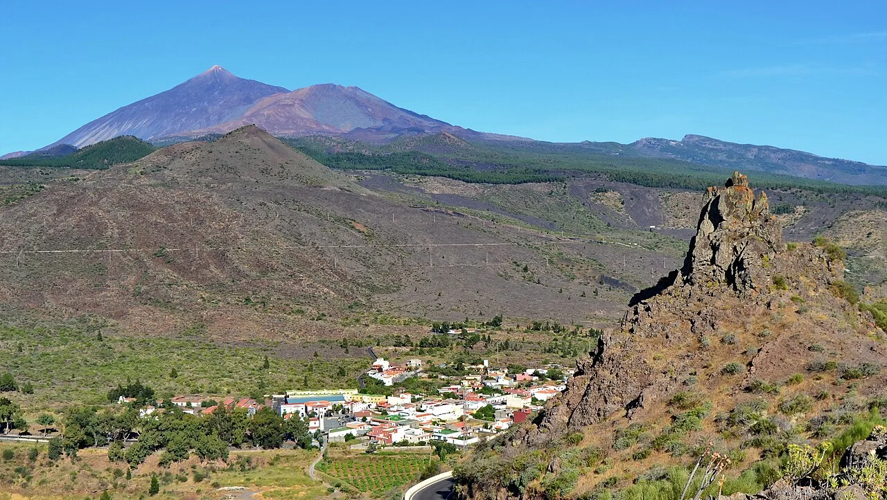Pueblo en un valle con montañas y volcán en el fondo.