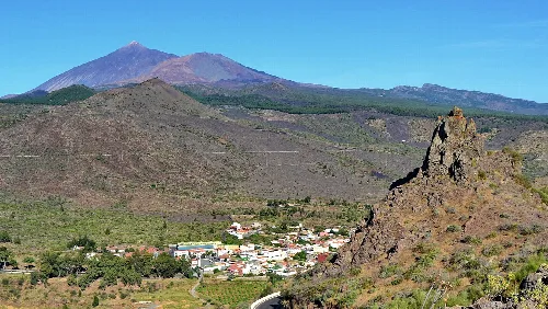 Village in a valley with mountains and volcano in the background.