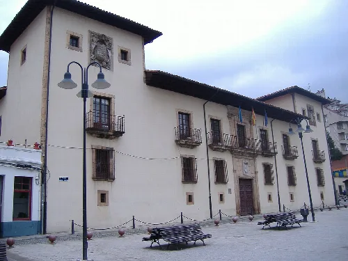 Edificio del ayuntamiento con banderas y bancos en la plaza de Cangas del Narcea.
