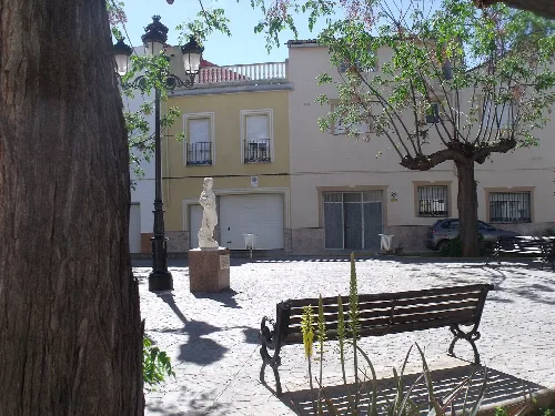 Platz mit Statue, Bänken und Bäumen in Cárcer.