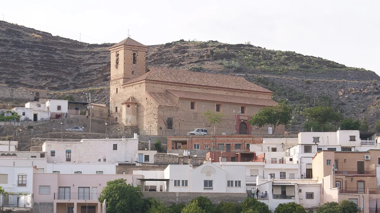 Iglesia de Gérgal en un paisaje urbano con casas blancas y colinas.
