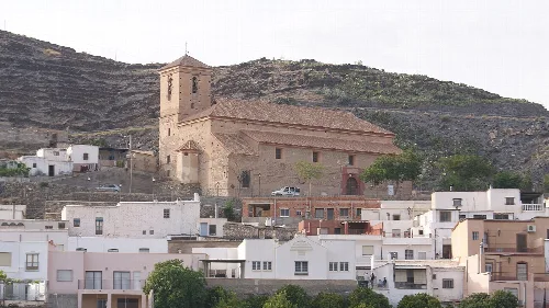 Iglesia de Gérgal en un paisaje urbano con casas blancas y colinas.