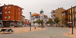 Plaza con reloj, árboles y bancos en La Robla, León.