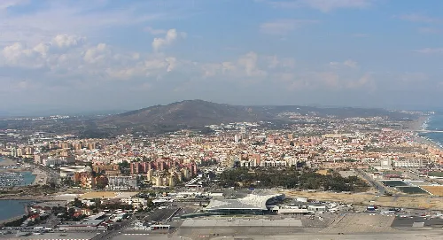 Luftaufnahme der Stadt mit Bergen und Meer im Hintergrund.