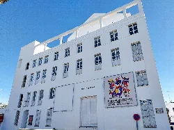 White theatre facade with a show poster and windows.