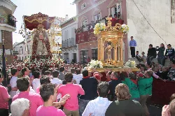 Crowd of people in a Pilas street watching a religious procession with decorated images.