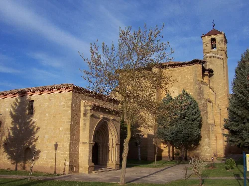 Parish church of Santa Cruz and hermitage in Bañares, La Rioja, with trees and blue sky.