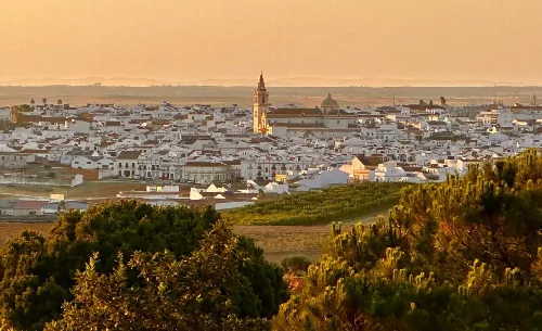 Landscape with white houses and a church in the center, cloudy sky.