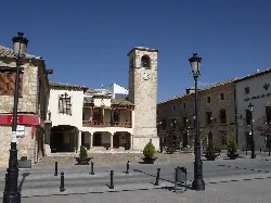 Main square with clock, lampposts, and stone buildings in Mota del Cuervo.