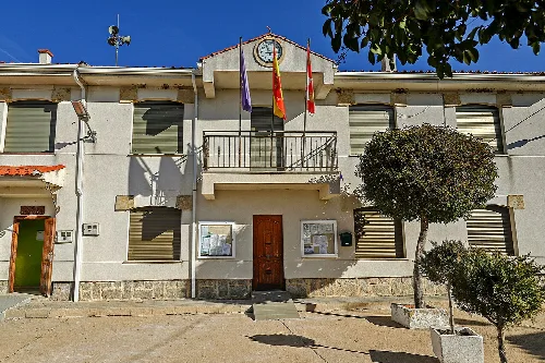 Edificio del ayuntamiento con banderas y reloj en la fachada.