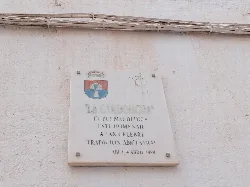 Placa blanca con escudo y texto en homenaje a la Cardoncha.