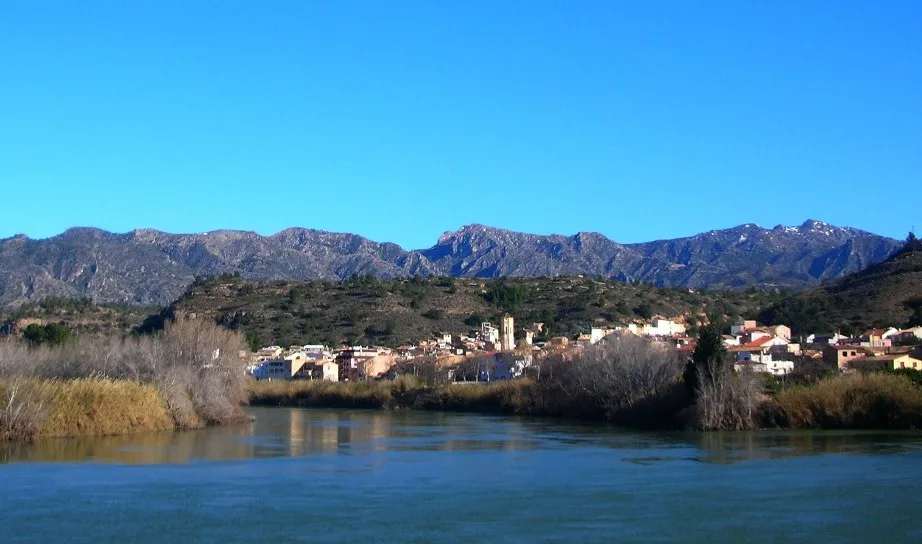 Tivenys, view of the village over the Ebre River. Serra de Cardó mountain range in the background