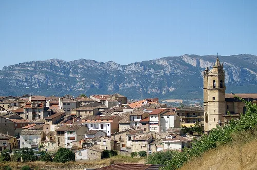 Städtische Landschaft von Elciego mit Häusern und Kirchturm, Berge im Hintergrund.