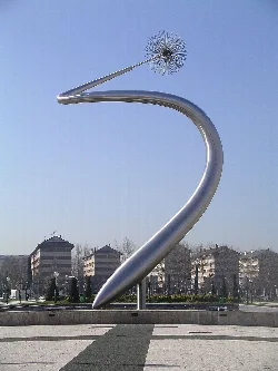 Escultura de una flor con tallo curvado y esfera en forma de diente de león en Vitoria.