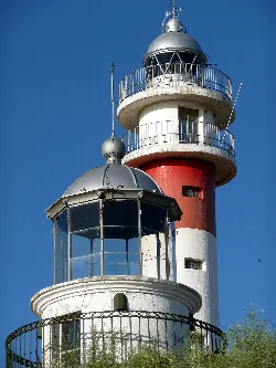 Two lighthouses in El Rompido, one with a metal dome and the other with glass structure and railing.