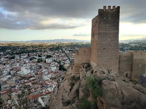 Burgturm auf einem Hügel mit Stadtblick.