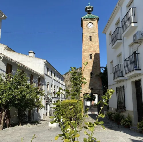 Uhrturm von Almedinilla mit Uhr und Kupferdach an einem sonnigen Tag.
