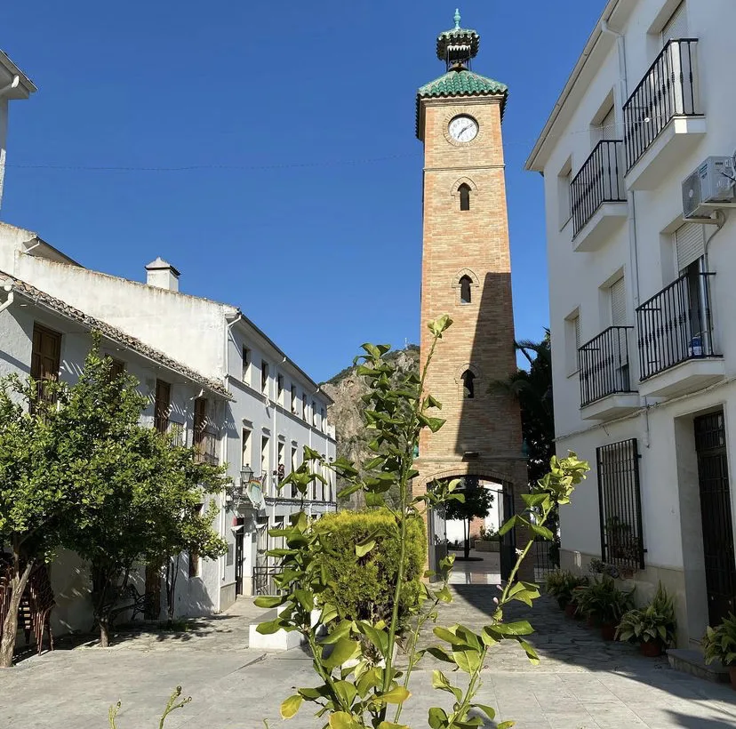 Torre del reloj de Almedinilla con reloj y tejado de cobre, en un día soleado.