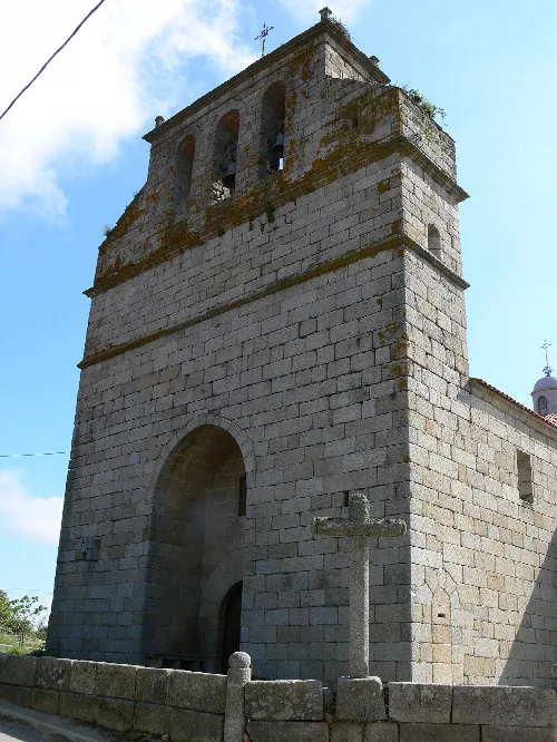 Stone bell tower of the Bogajo parish church with cross at the top.