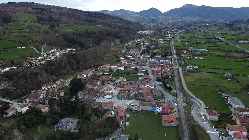 Vista panorámica de Arenas de Iguña desde el sur, con calles, casas y montañas.