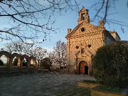 Small church with bell tower and arched entrance in a peaceful setting.