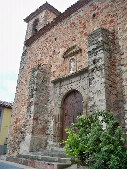 Puerta de madera de la iglesia con arco de piedra y escultura en la parte superior.