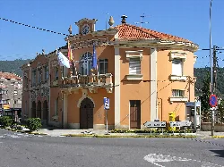 Edificio de color naranja con banderas y señal de tráfico en la calle.