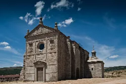 Steinernes Kloster mit schlichter Fassade und blauem Himmel mit Wolken.