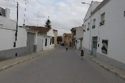 Vista de una calle con casas blancas y niños jugando en Villalpardo.