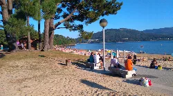 People sitting on benches and on the beach in Outes, Galicia.
