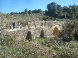 Stone bridge with arches in Sant Mateu, surrounded by vegetation and trees.