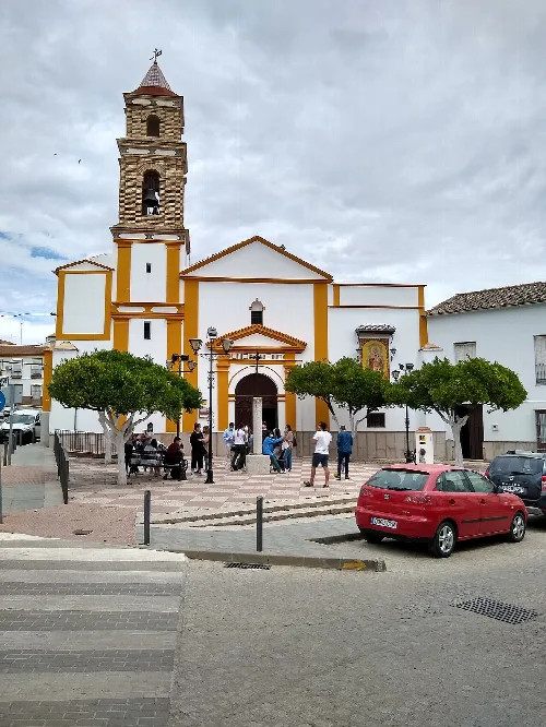 Church of San Marcos Evangelista in El Saucejo, with trees and people in the square.
