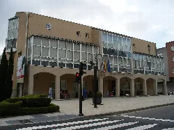 Building with large windows and flags at the entrance in Arteijo.