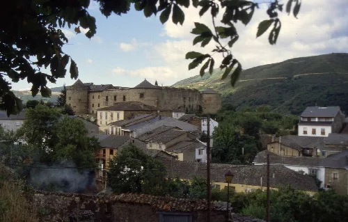 Panoramablick auf Villafranca del Bierzo mit Burg und Häusern in den Bergen.
