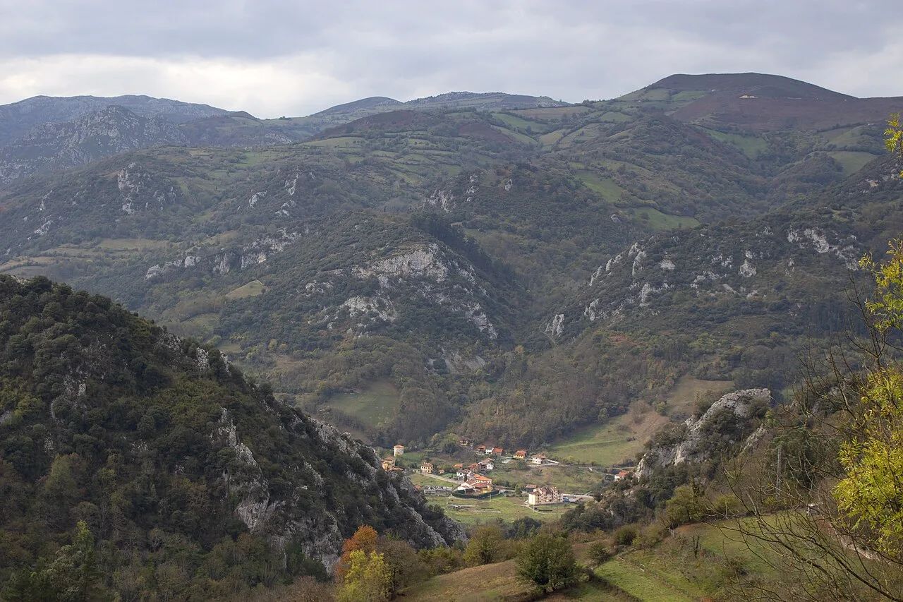 Landschaft mit grünen Bergen und Häusern im Tal in Proaza, Asturien.