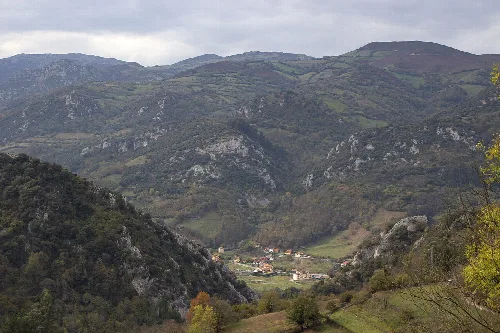 Paisaje de montañas verdes y casas en un valle en Proaza, Asturias.