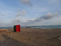 Beach cabins on the sand with the sea and sky in the background.