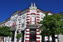 Edificio con fachada blanca y detalles en rojo en Cortegana.