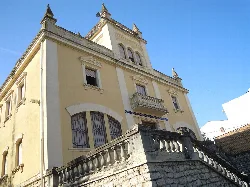 Edificio de color amarillo con torre y balcón en Buñol.