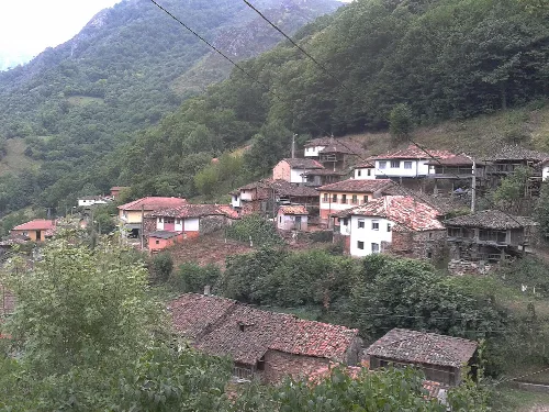 Casas y cuevas en una ladera en Belmonte de Miranda, Asturias.