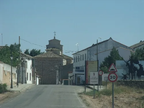Straße, die nach Casas de los Pinos führt, mit Schildern und Wandbild.