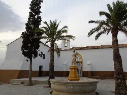 Saint Sebastian hermitage with palms and monument in the square.