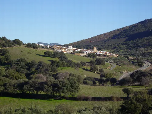 Panoramic view of Romangordo with white houses and green mountains.