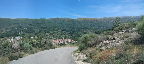 Ländliche Straße mit Vegetation und Bergen im Hintergrund in Cáceres