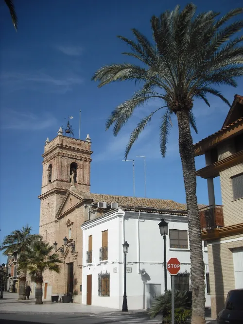 Kirche von Albuixech mit Turm und Palmen im Vordergrund.
