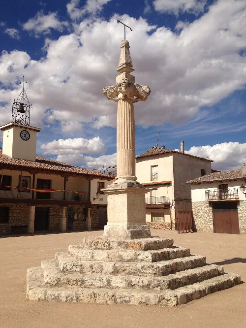 Pillar in Lupiana's Main Square with buildings and cloudy sky.