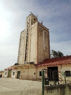 Silo alto de cemento con edificio en la base y cielo despejado.