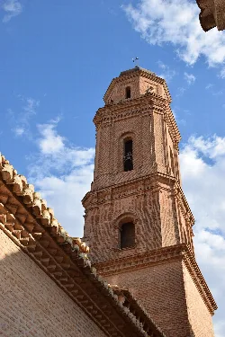 Brick bell tower of the church with blue sky and clouds.