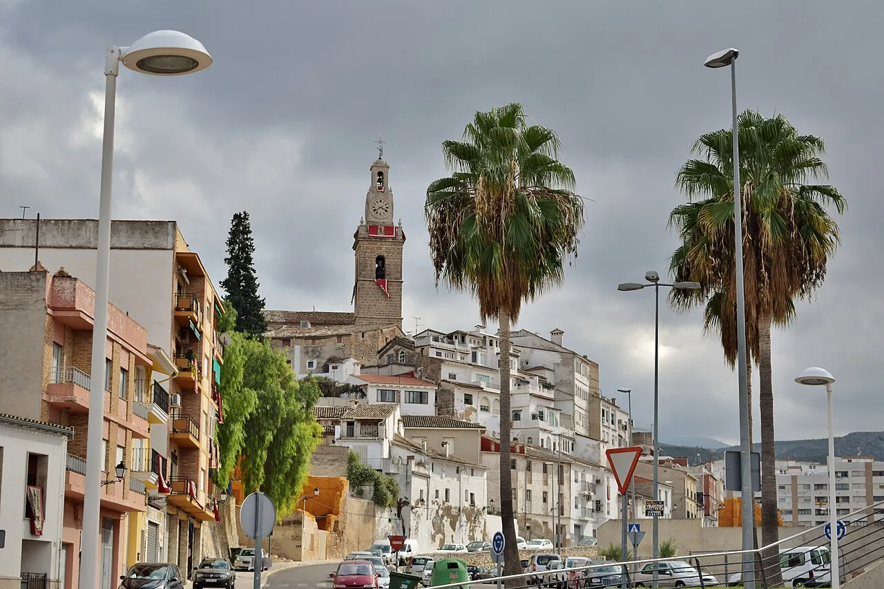 Vista de Albaida con casas blancas, palmeras y una torre en la colina.